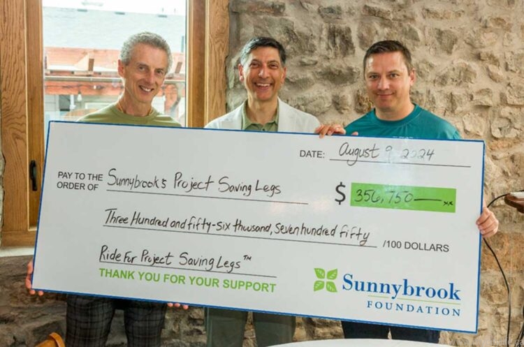 2 participants or Ride for Project Saving Legs and Dr. Giuseppe Papia holding a large donation check to Sunnybrook Hospital.